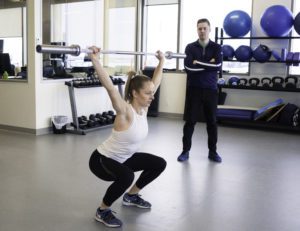 woman excercising with physiotherapist near by
