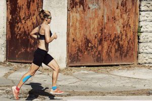 athletic woman running in street with taped shin and ankle